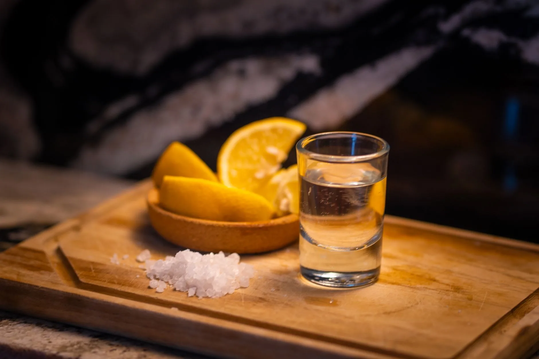 Verre de tequila avec sel et quartiers de citron sur une planche en bois